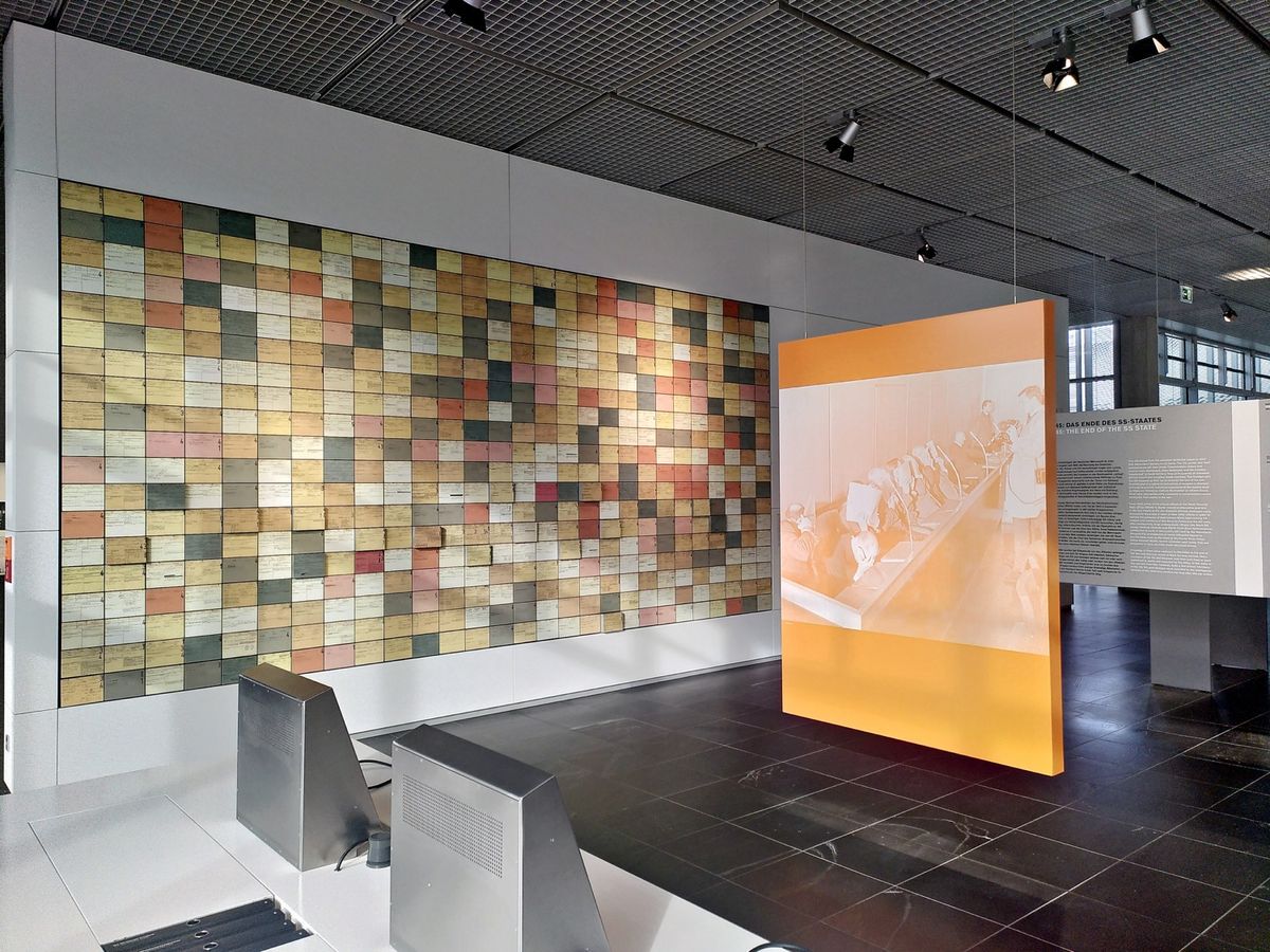 Rasterförmig angeordnete, farbige Karteikarten an einer Wand, die im Rahmen einer Ausstellung gezeigt werden.